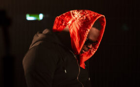 Nigerian rapper Yung Sammy wearing a red bandana and black jacket in the video for 'The Intro' for DESI TRILL