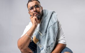 Vasu Kainth wearing glasses holding blue denim jacket