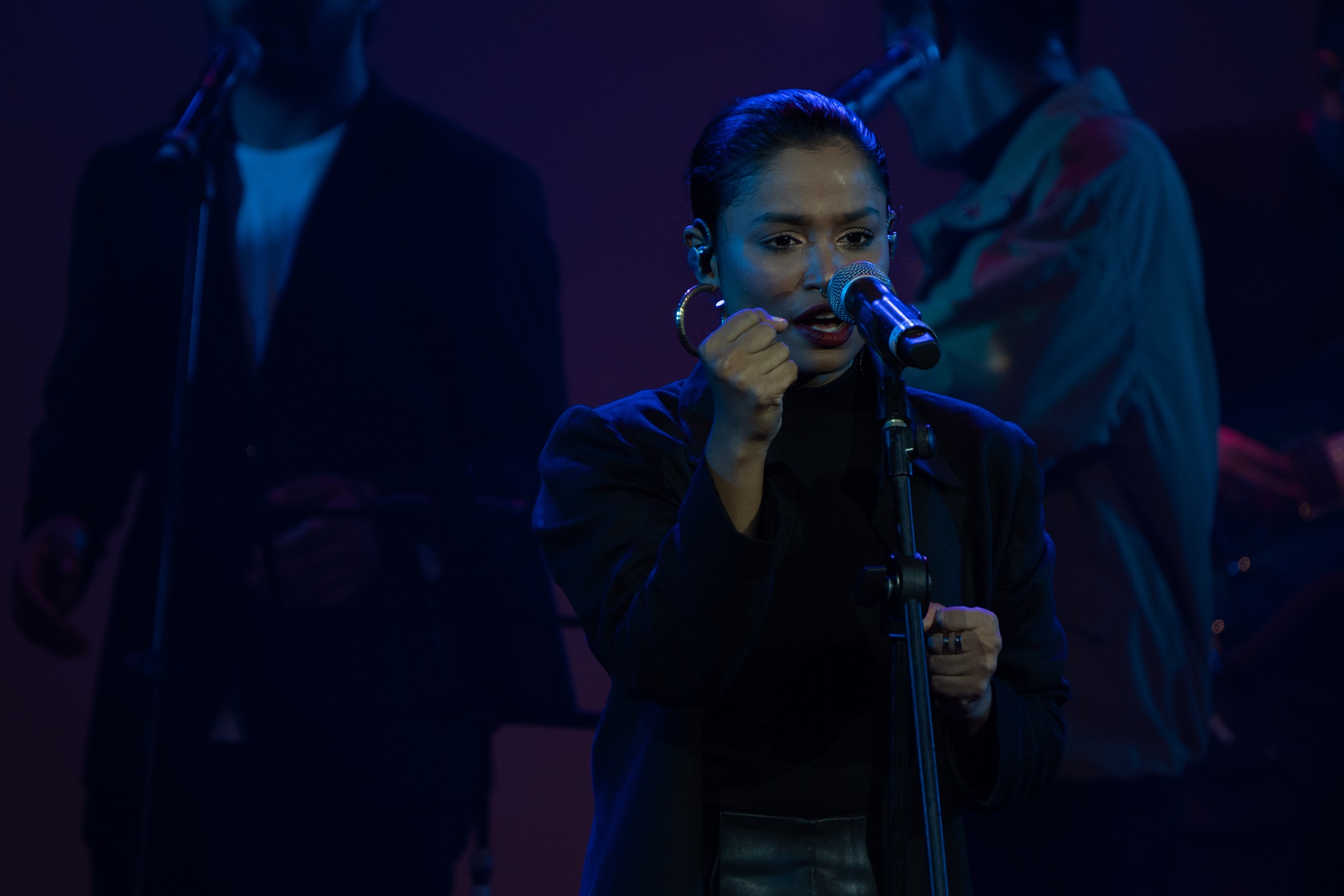 Arunaja wearing black and singing with hand raised