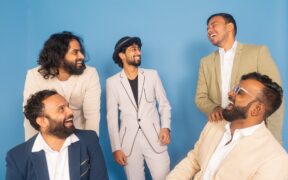 Last Minute India band members in suits standing on blue background