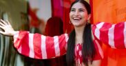 Sai Godbole in a red and white dress, smiling