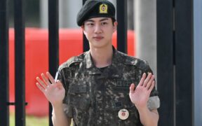 Jin waves after being discharged from his mandatory military service outside a military base