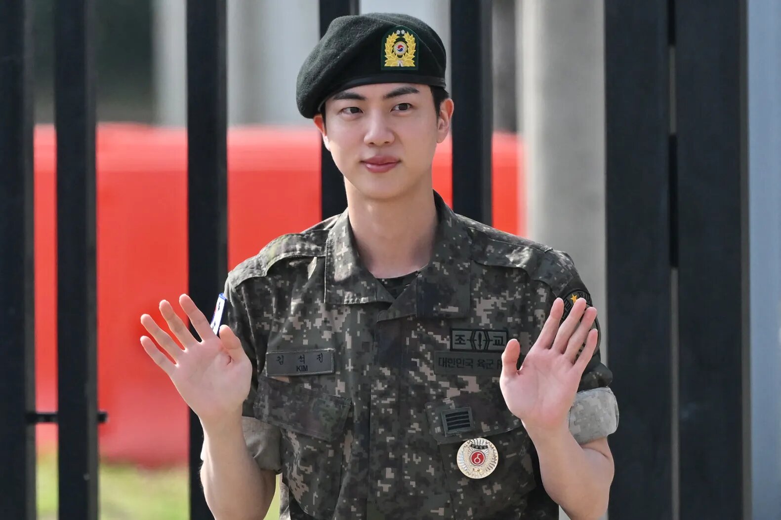 Jin waves after being discharged from his mandatory military service outside a military base