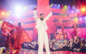 Karan Aujla wearing white and performing on stage