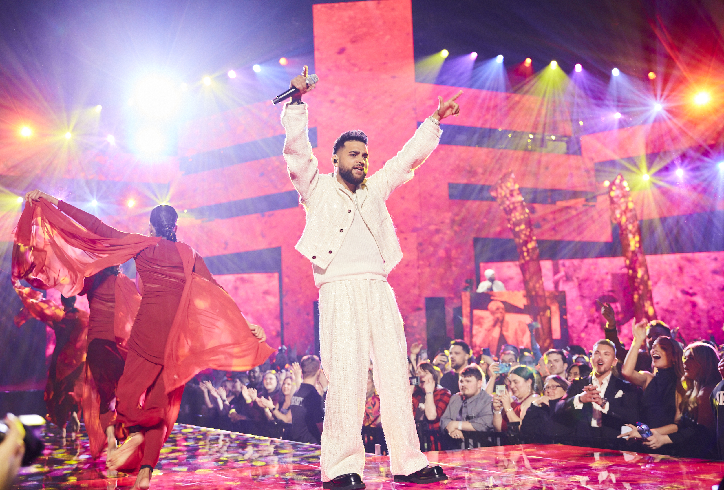 Karan Aujla wearing white and performing on stage