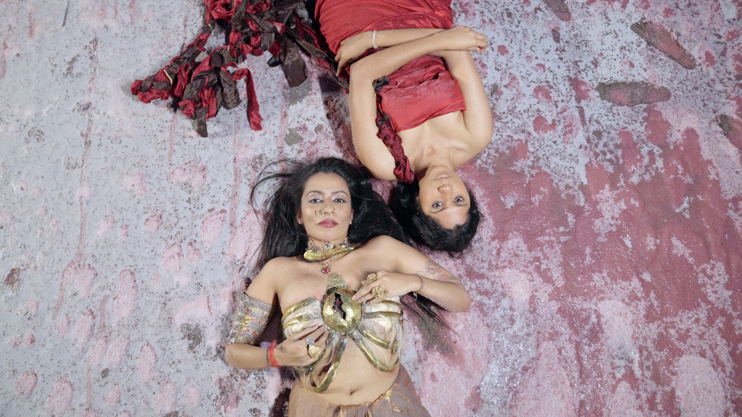 Ganavya and Shilo Shiv Suleman laying across from each other on a salt plain patch