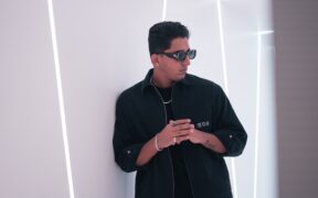 GNDHI aka Rohit Gandhi wearing black standing in white room