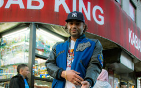 New York artist Heems aka Himanshu Suri in blue jacket and black cap standing outside a kebab shop