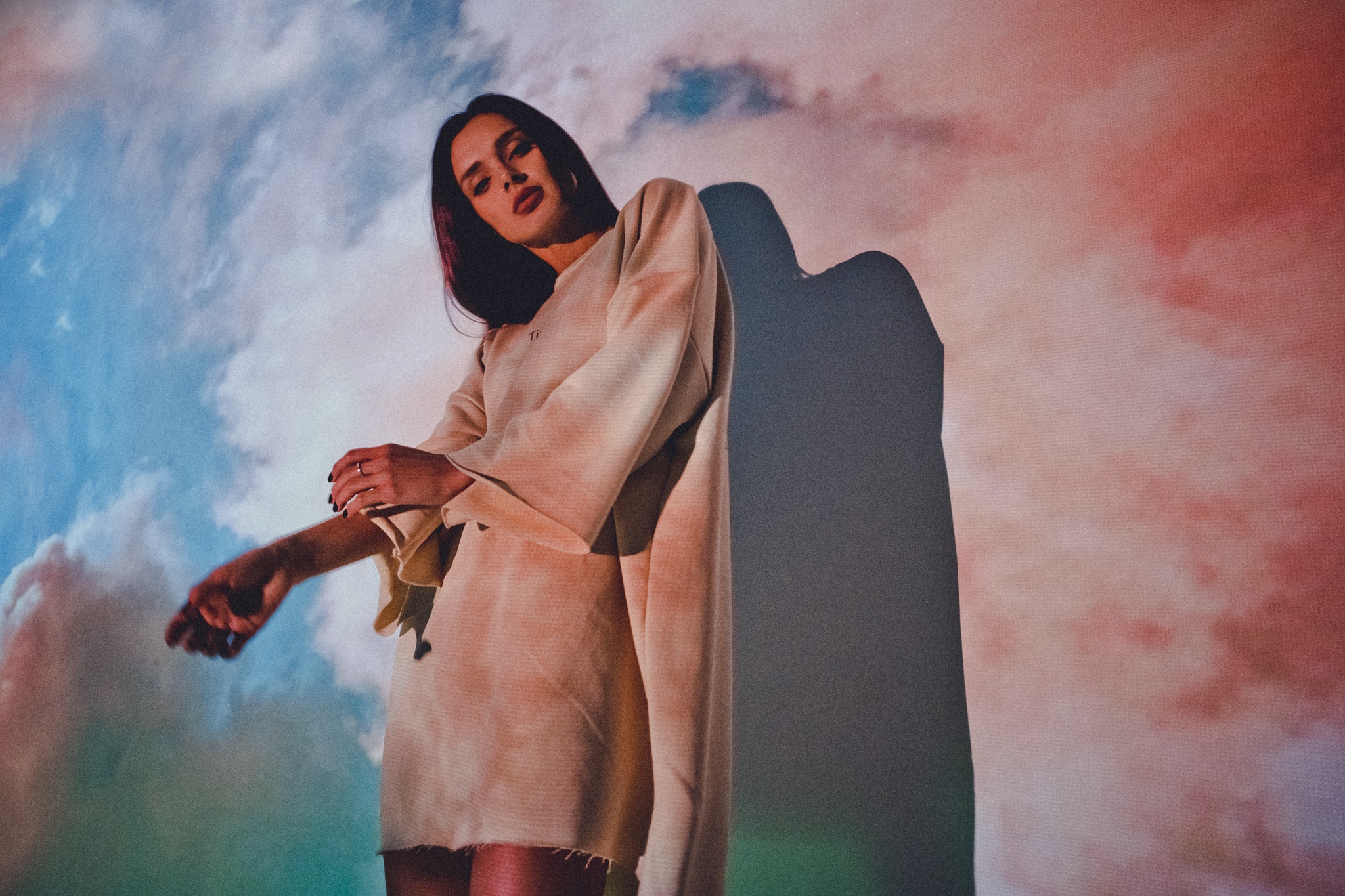 Korolova in a white dress with projected colors in the background