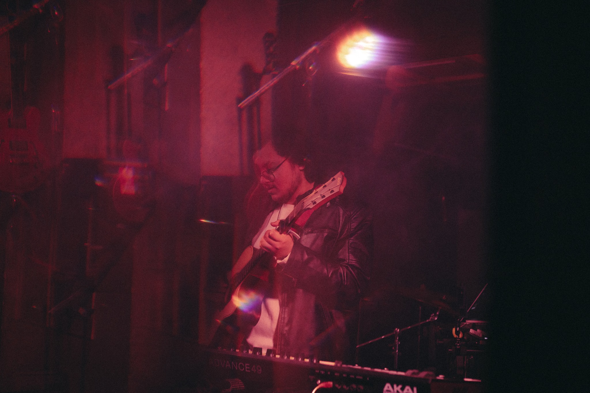 Shivang Arora playing guitar on stage in red light