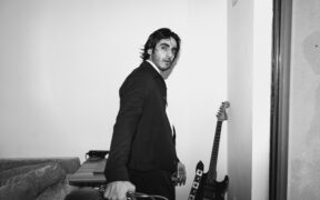 Danish Pratap Sood wearing black suit carrying a guitar amplifier