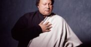 Nusrat Fateh Ali Khan in a black shirt with white shawl holding his hand to chest, with eyes closed