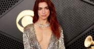 Dua Lipa with red hair, wearing a low cut gown