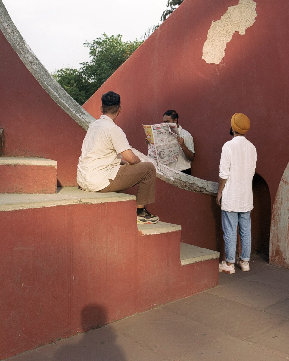 Members of music group Excise Dept sitting on steps, one of them reading newspaper