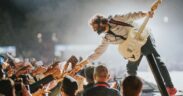 Arijit Singh holding guitar and outstretching his hand to greet fans on stage