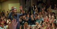 Bobby McFerrin raising his hands in a group of people at a concert workshop