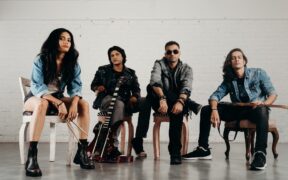 Members of Mumbai rock band Contra seated and posing for a photo with their instrumentsi ncluding bass guitar and electric guitar and drumsticks