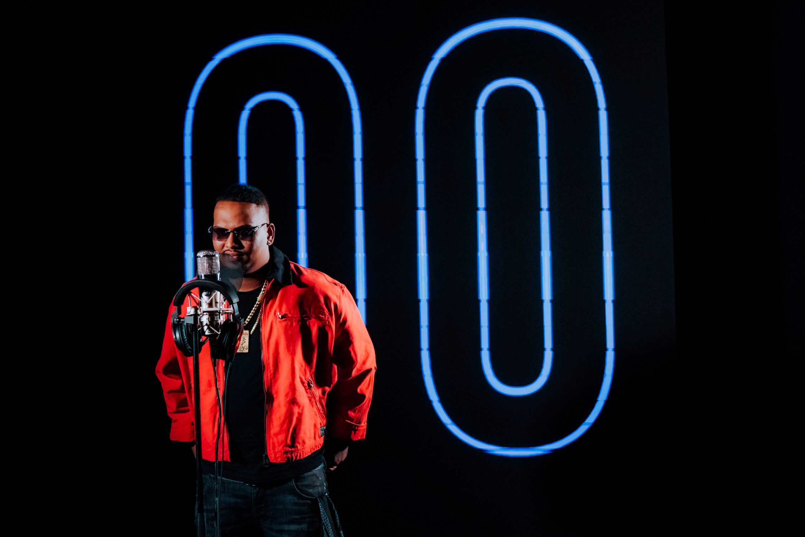 Sambata in glasses and red jacket, in front of a mic