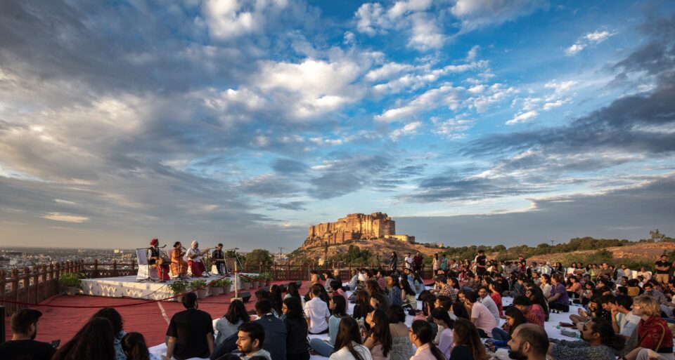 Crowd gathered to watch a performance of artists under blue sky at Mehrangarh Fort