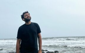 Kaushal Kishore on a beach wearing a black t-shirt