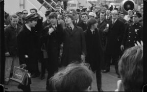 The Beatles departing from their plane to a sea of press in Disney's BEATLES '64