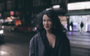 Anoushka Shankar wearing black jacket posing for photo outside on the street