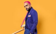 Sanjeev T aka Kulture Cid wearing blue coat and pants, pink hair and holding white guitar