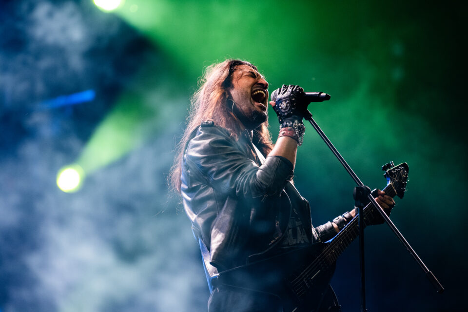 Girish Pradhan sings into a mic while holding a guitar