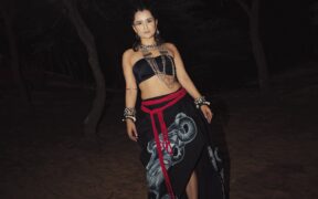 Singer Sharvi Yadav wearing a black top and skirt in a dark backdrop with trees around her