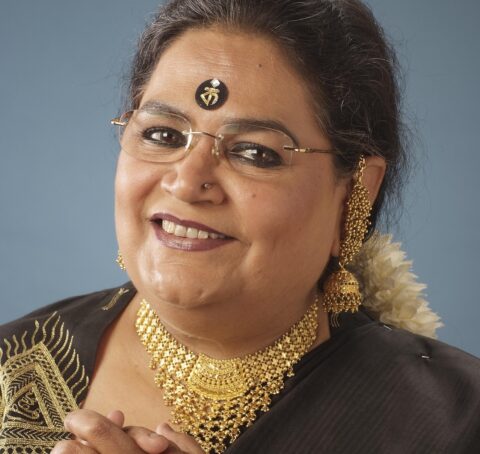 Usha Uthup in a black saree, wearing gold necklace