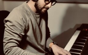 Composer and producer Rishabh Shah playing piano with headphones on