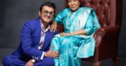 Sonu Nigam in blue suit sitting on the ground next to Asha Bhosle in cyan blue sari on a chair