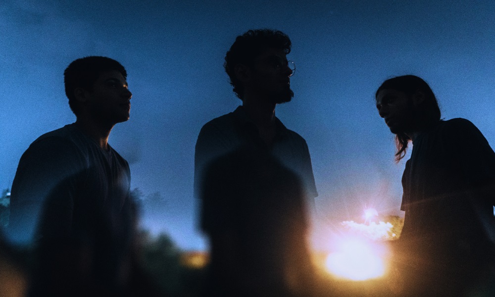 Zokova band members in the dark, with blue background and sunlight