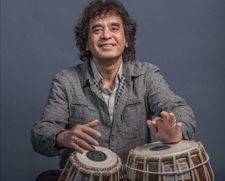 Tabla legend Zakir Hussain in a grey jacket playing tabla