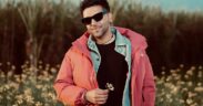 Guru Randhawa wearing red jacket standing in greenery