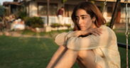 Jonita Gandhi sitting on a swing outdoors wearing beige dress