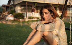 Jonita Gandhi sitting on a swing outdoors wearing beige dress