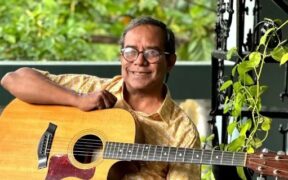 Susmit Sen with guitar, smiling