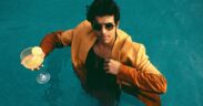 Singer Tarang Joseph in a pool wearing a suit with sunglasses and glass in hand