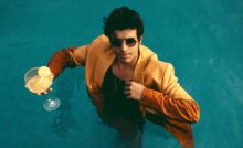 Singer Tarang Joseph in a pool wearing a suit with sunglasses and glass in hand