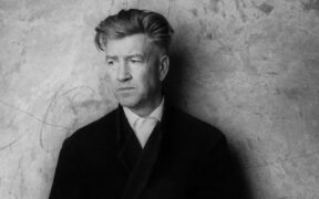 David Lynch wearing a black coat over a white shirt