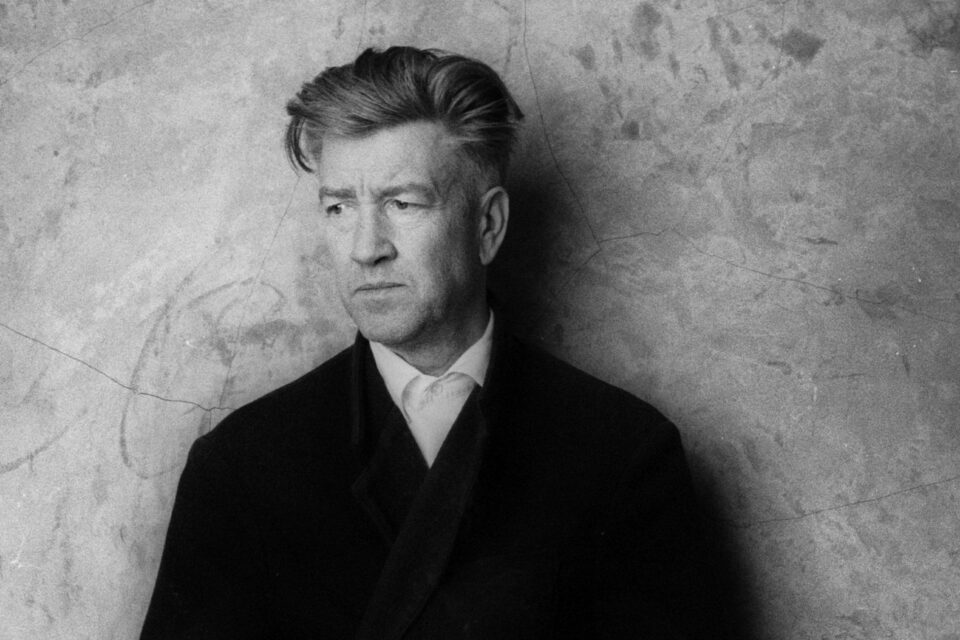 David Lynch wearing a black coat over a white shirt