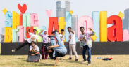 Hip-hop artists from Dharavi posing in front of a sign reading Shine Bright at Lolla