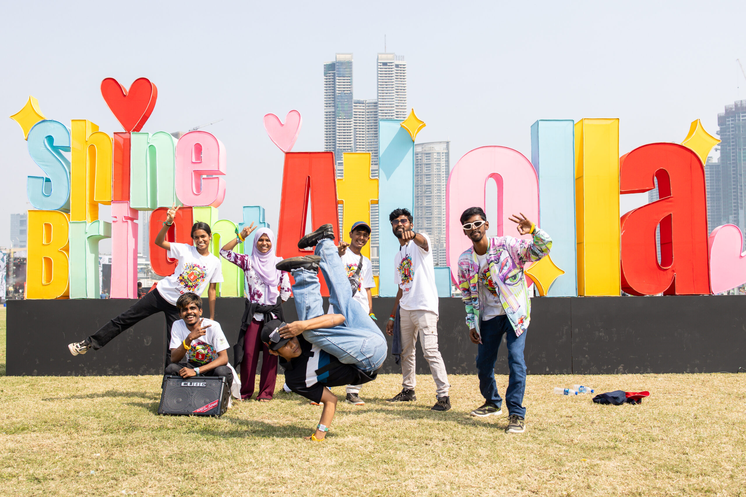 Hip-hop artists from Dharavi posing in front of a sign reading Shine Bright at Lolla