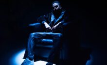 Rapper DRV aka Dhruv Rajpal wearing black seated on a couch under a spotlight