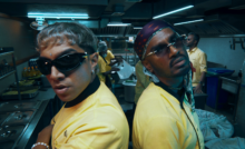 Rappers Yung Raja and SVDP wearing yellow chef uniforms in a kitchen