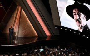 An image of late US actor Gene Hackman is seen on a screen as US actor Morgan Freeman stands onstage during the 97th Annual Academy Awards at the Dolby Theatre in Hollywood, California