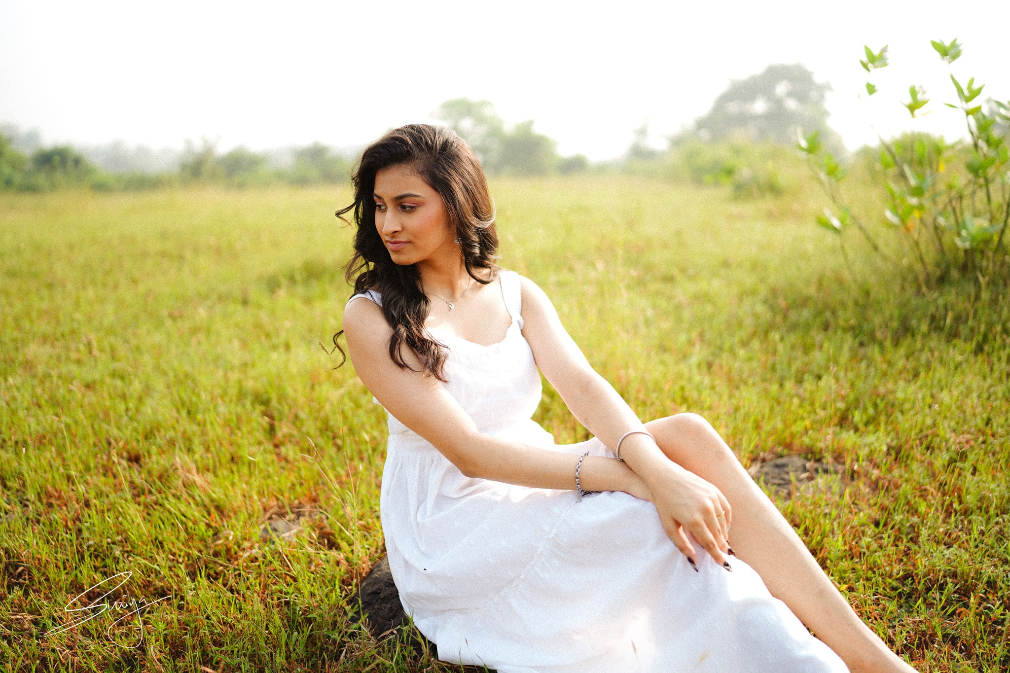 Pop artist Shriya Rao in a white dress, sitting on grass