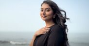 Vidhi Poddar in black dress looking into camera with sea in the background